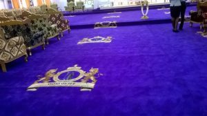 The purple carpet inside the palace hall, imprinted with the Ooni of Ife crest, leading toward the royal seating area.